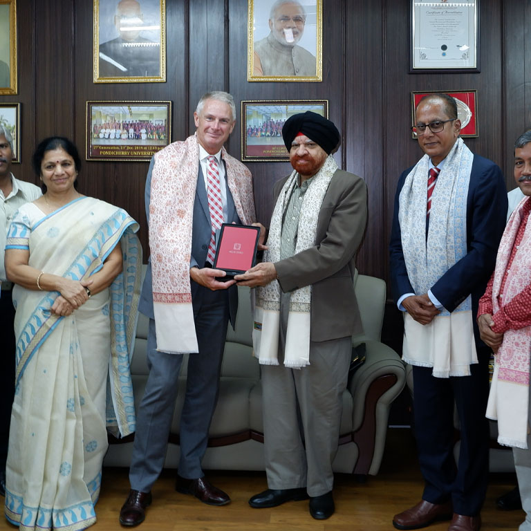 A group of four men and one woman hold a framed certificate and pose for a picture