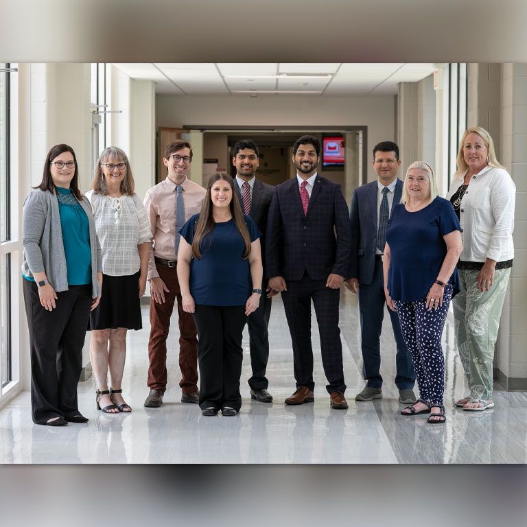 Five women and four men pose in a group