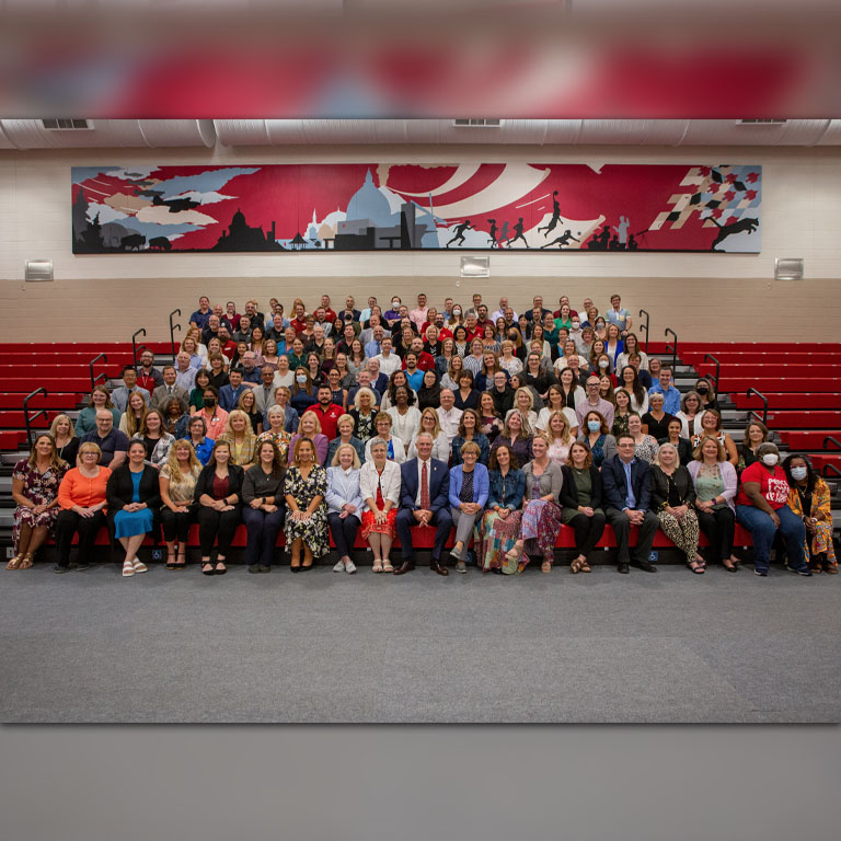 A large group of people pose on bleachers