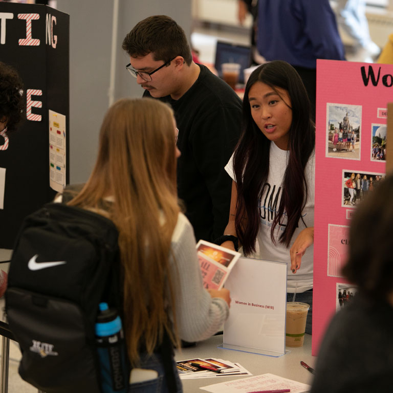 A man and woman talk to a woman behind a poster