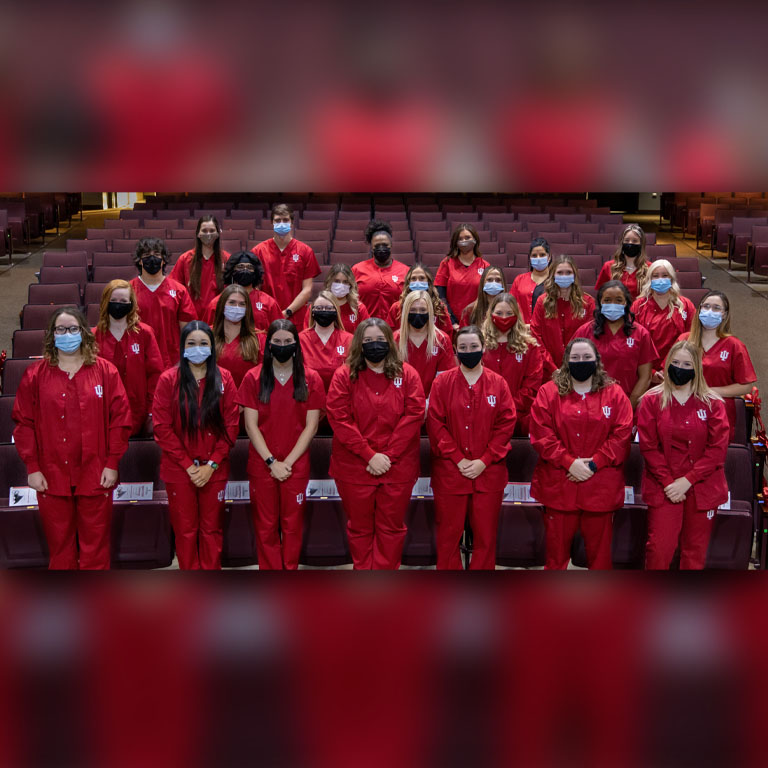 Four rows of people in red scrubs
