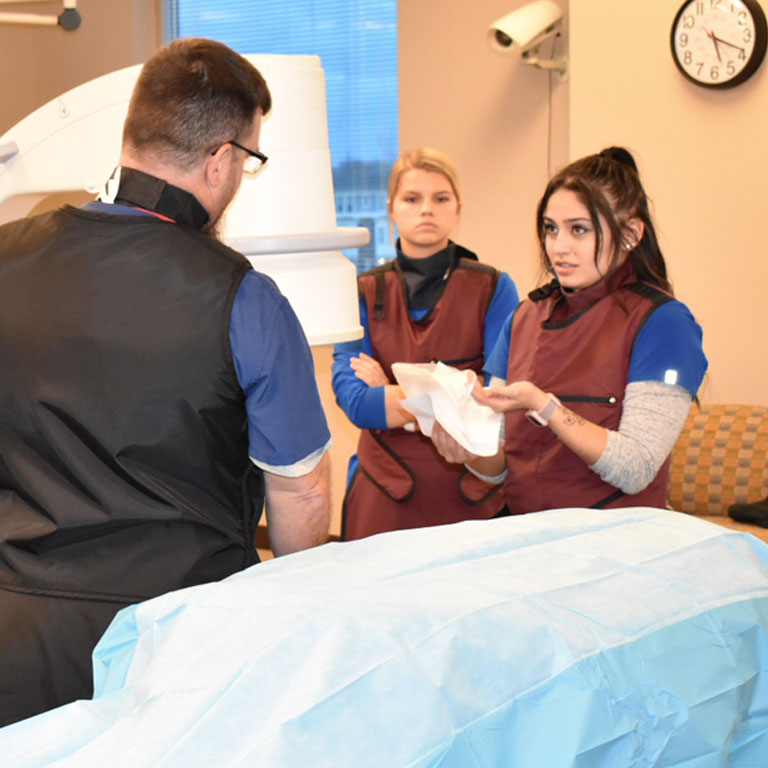 Three people work with a medical imaging machine