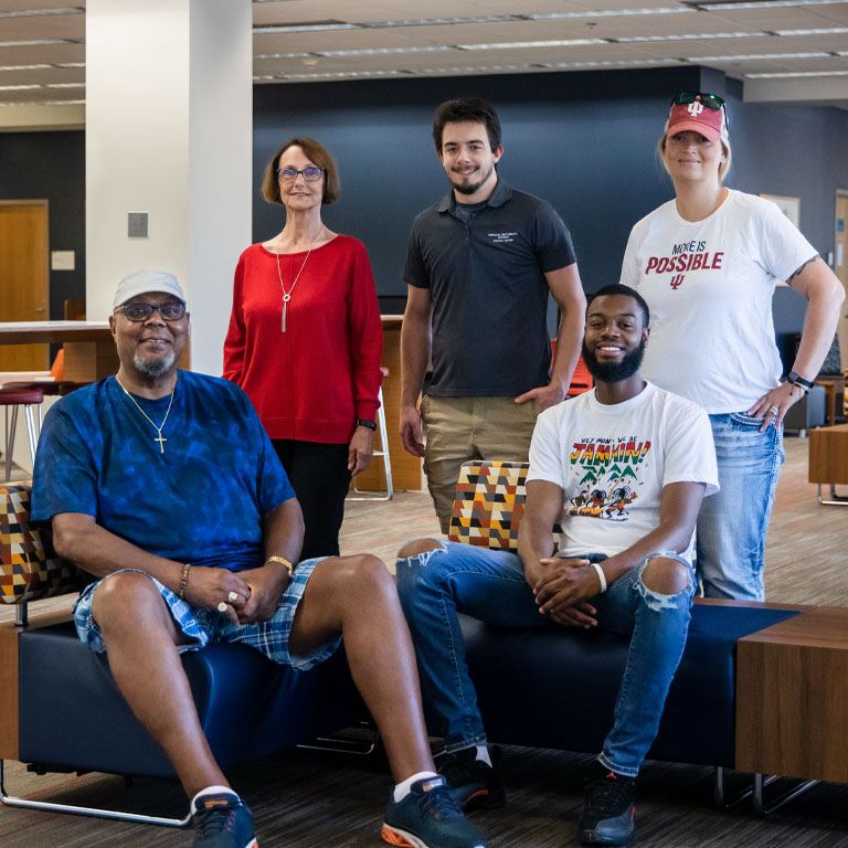 Three men and two women pose in the library.