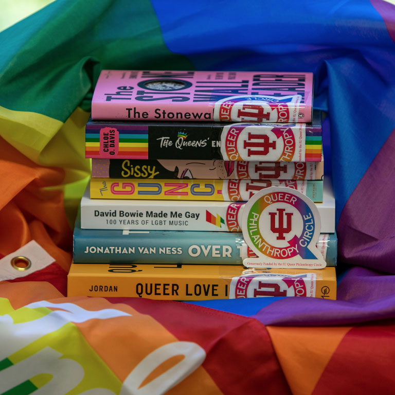 A stack of books on a rainbow Pride flag