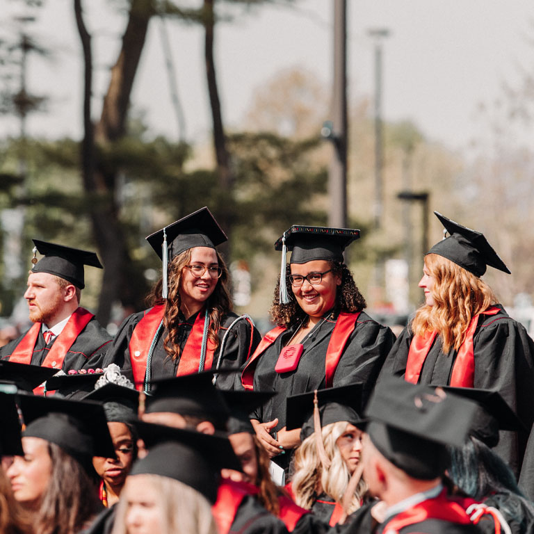 Five graduates stand in a row