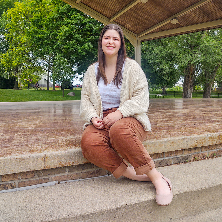 A student poses on an outdoor stage