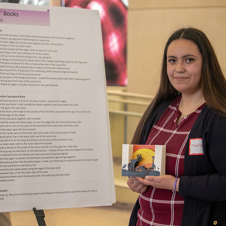 A woman stands in front of a research poster