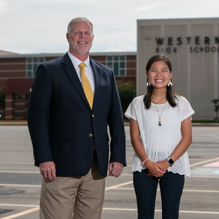 A man and a woman stand in front of a high school