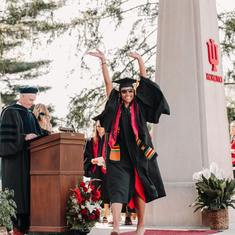 student waving arms on commencement stage