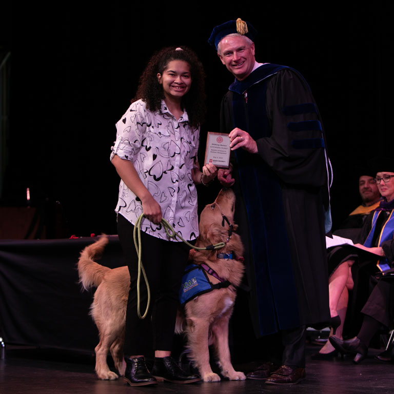 student with her service dog receiving honors award