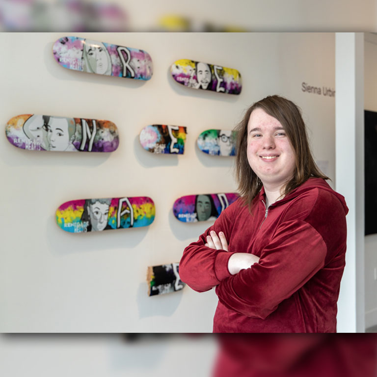A person stands with painted skateboards
