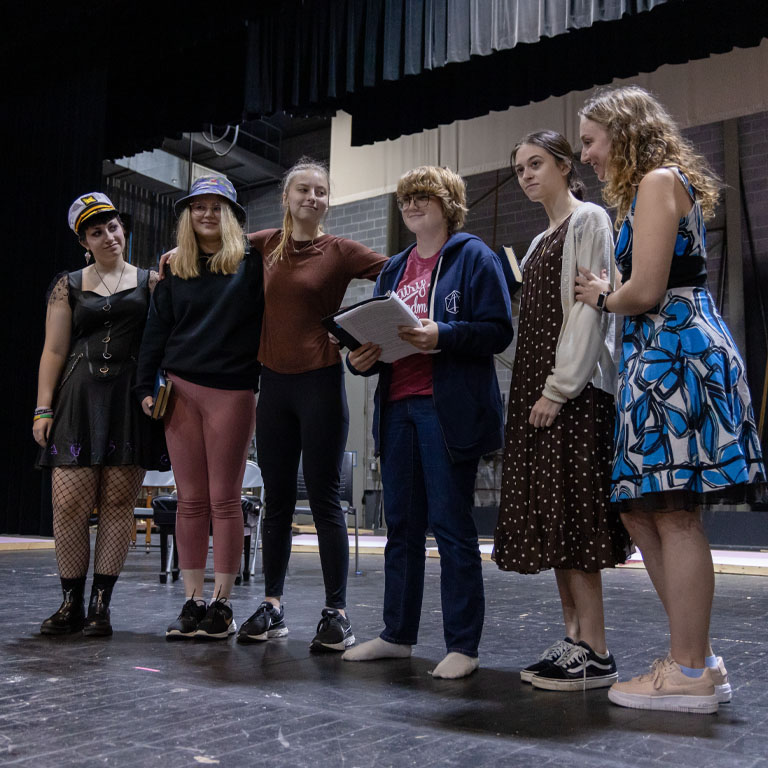 Five students stand on a stage