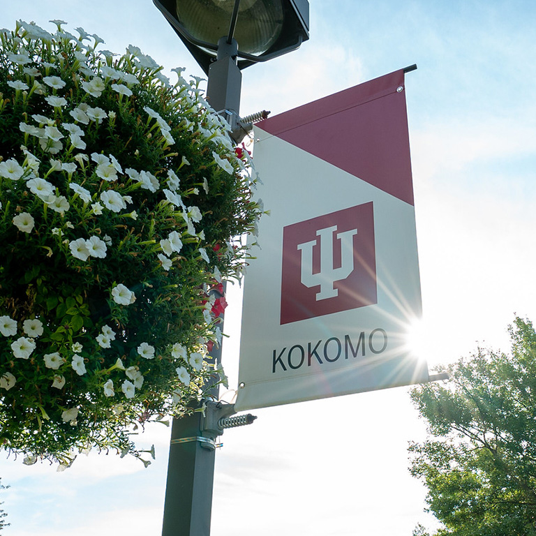 A basket of white petunias in front of a red and white IU banner