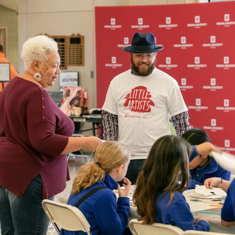 A woman and a man stand at a table with children.