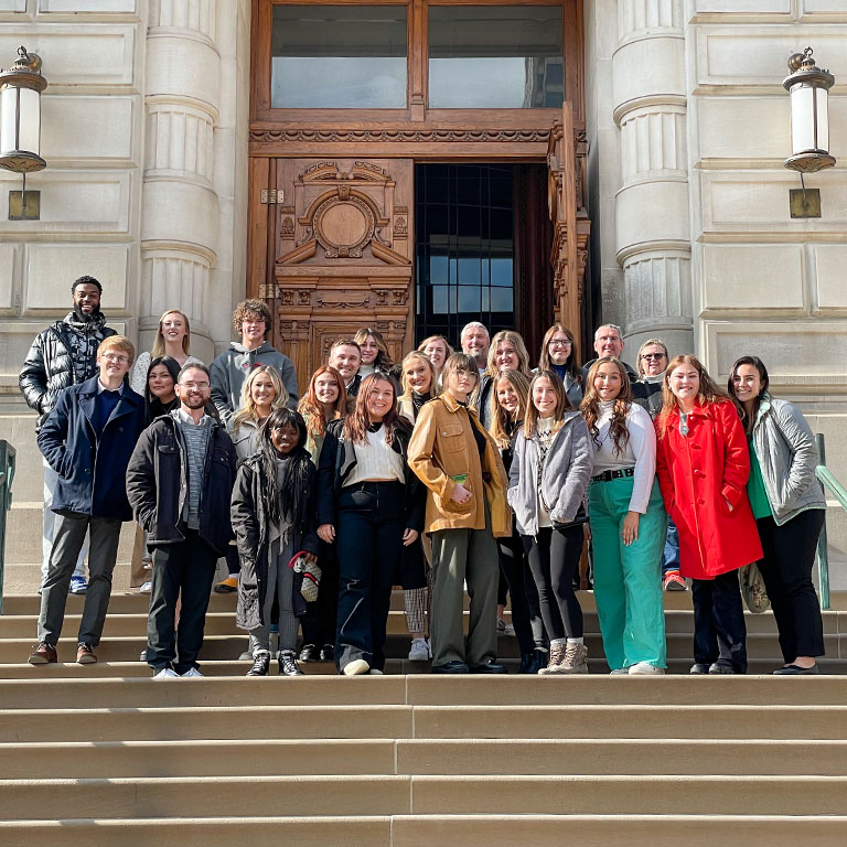 A group of people stand on the steps outside the Indiana Statehouse