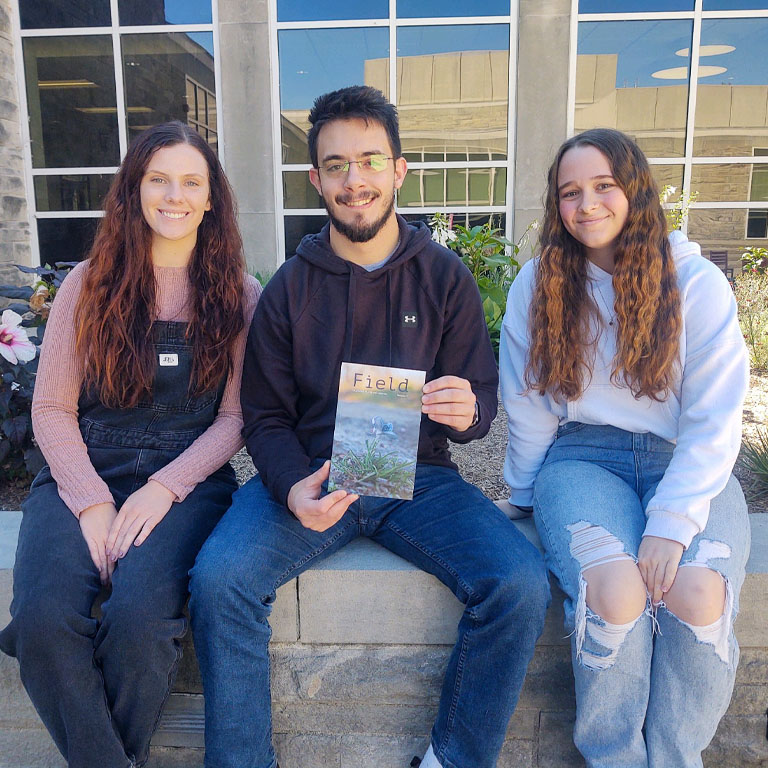 Two women and one man pose with a magazine