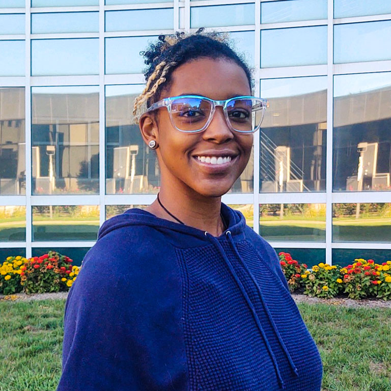 A woman poses in front of a glass wall.