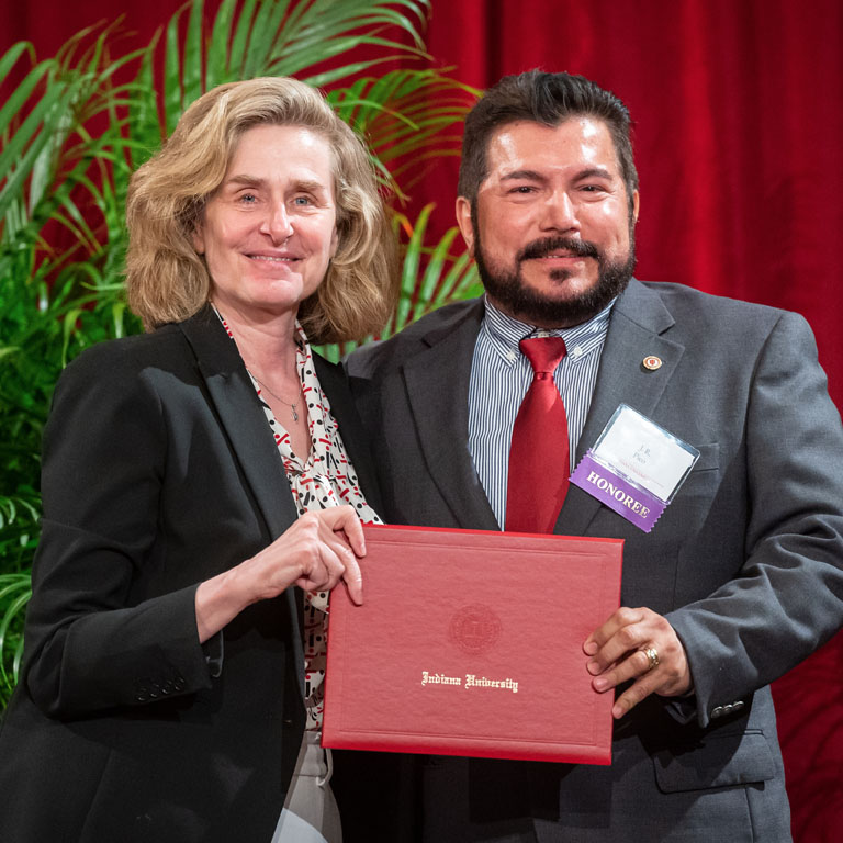 A woman and a man pose for a picture holding an award certificate