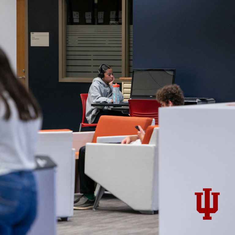 A woman sits at a table using a laptop