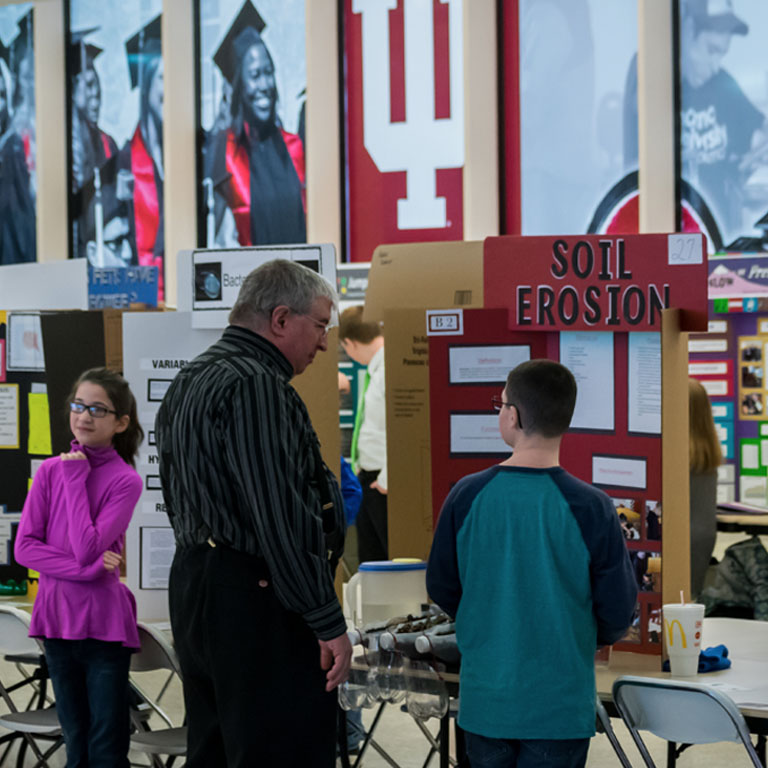 A man and a boy look at a science fair project poster.