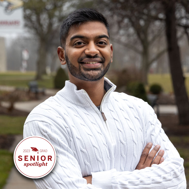 A man in a white sweater poses for a picture