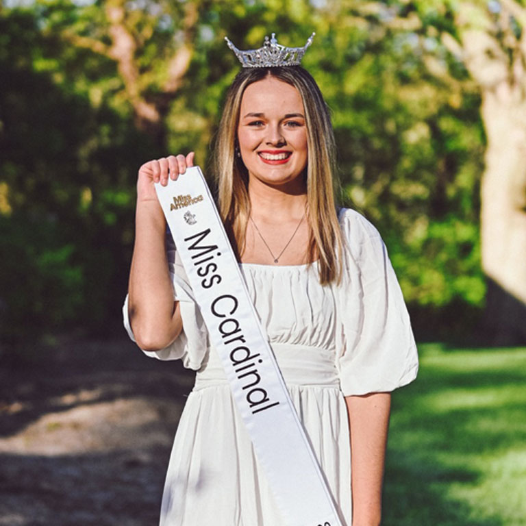 A woman wearing a crown holds a banner