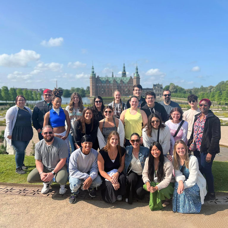 A group of people pose in front of a castle