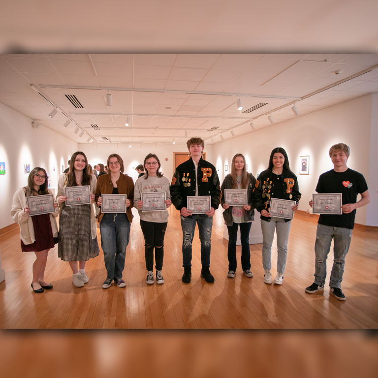 Eight students stand in a line with certificates