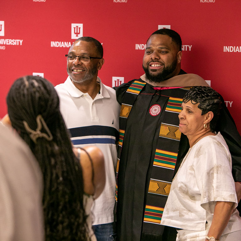 A group of people gather for a picture in front of a red backdrop.