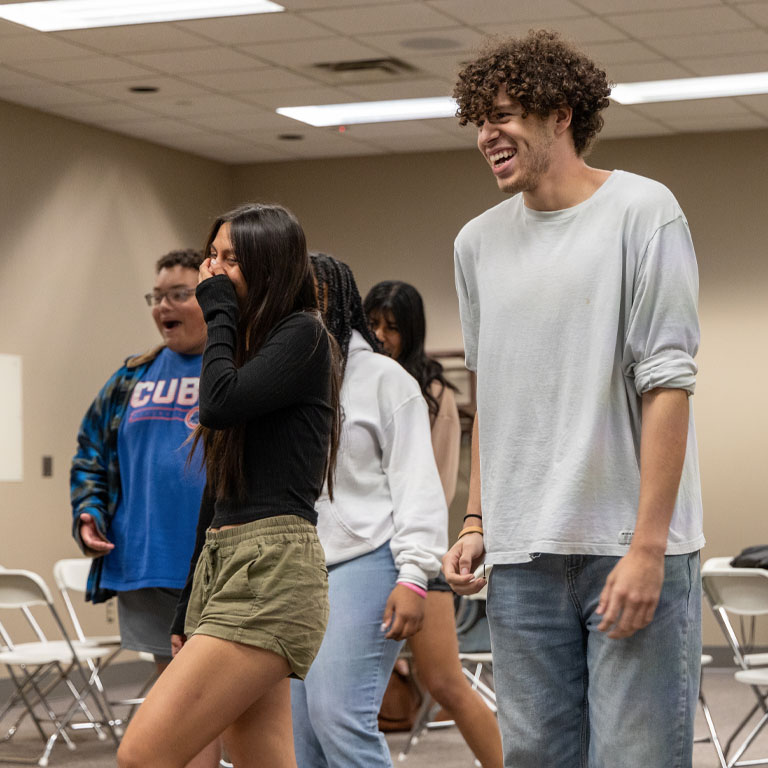 A woman and a man laugh in a classroom