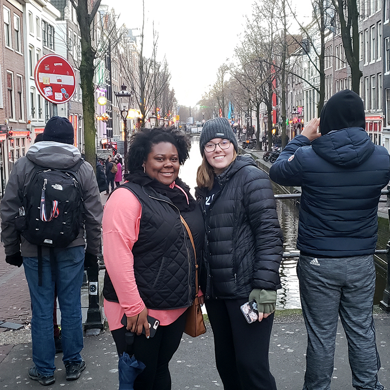 Two women smile on a bridge in Amsterdam
