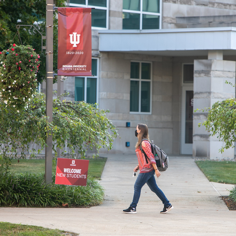 A woman with a backpack walks in front of a limestone building