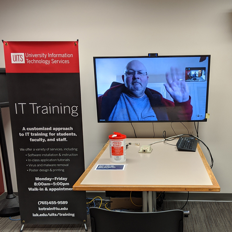 A man waves from a computer screen image