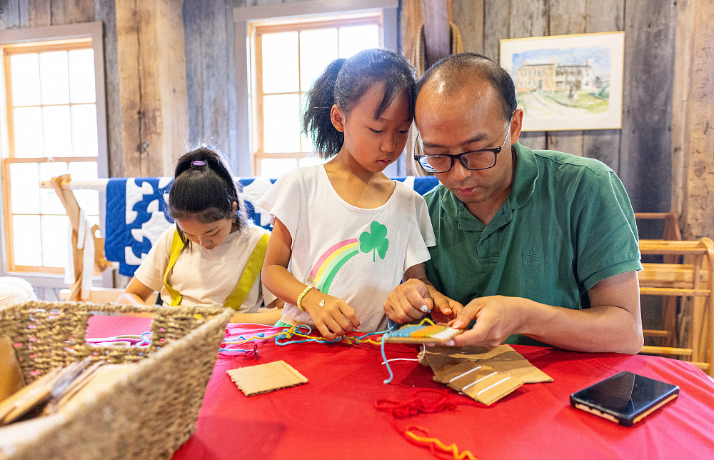 Zitong and Ziyang Yan and their father Sheng Yan use string and yarn to weave during the Wylie House Museum's Saturday Crafternoon activi...