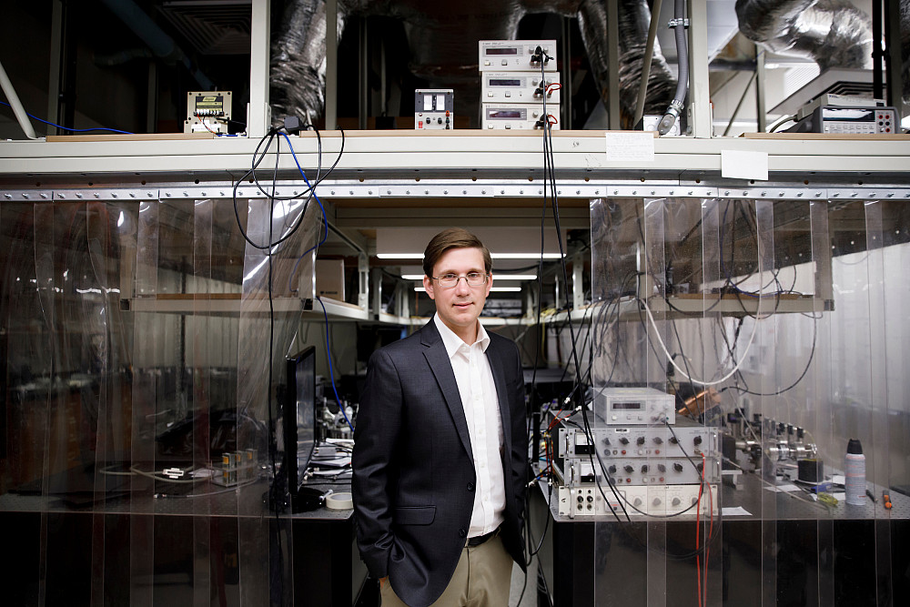 Indiana University Professor Phil Richerme poses for a portrait in front of laser equipment in his Simon Hall lab at IU Bloomington on We...