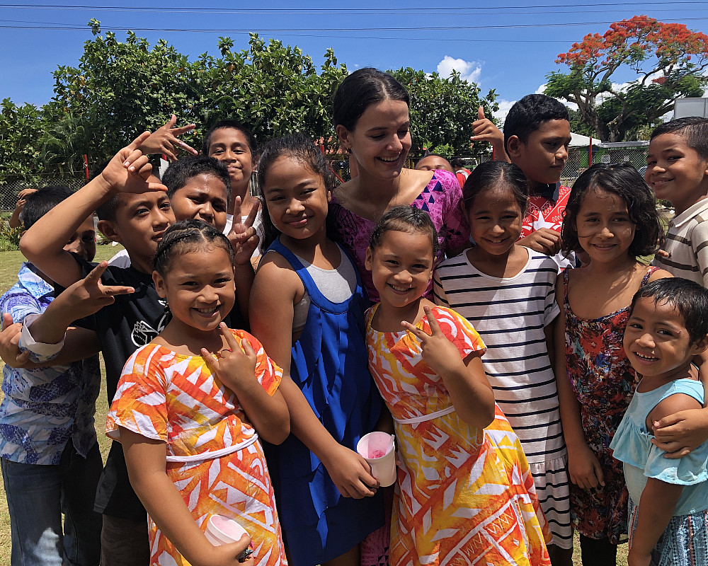 A woman poses with students in Samoa.
