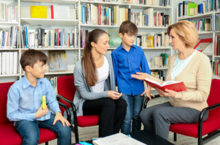 Young mother and children on meeting with teacher at school
