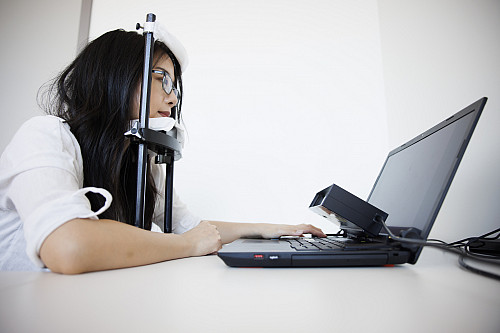 A woman reads text on a screen with eye tracker
