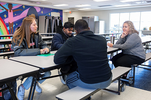 Four people sit around a cafeteria-style table talking