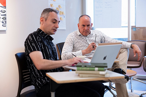 Gürkan Mihçi and Robert Swazo work together at a computer.