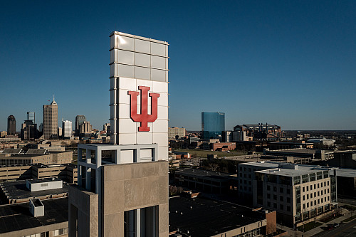 The IU trident sits above the Campus Center bell tower at IUPUI, with the Indianapolis skyline in the background. The photo was taken on ...