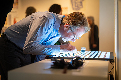 A man looks closely at 16mm film strips.