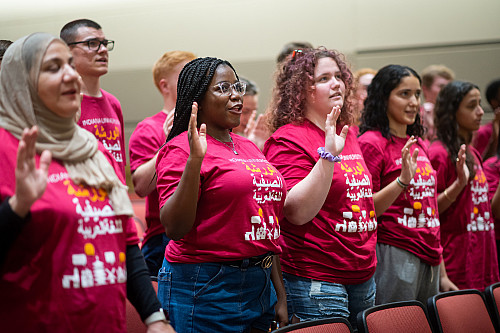 Students in red shirts hold up their hands