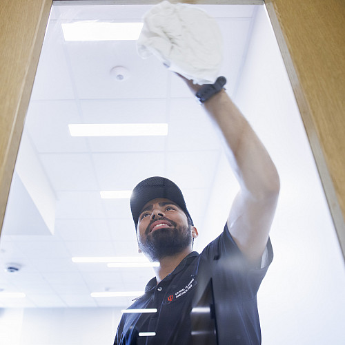 Custodian Jose Gutierrez Vasquez cleans a door's window at the Luddy Center for Artificial Intelligence. Photo by James Brosher, Indiana ...