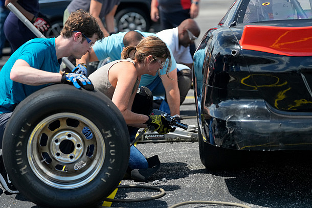 A woman changes a race car tire
