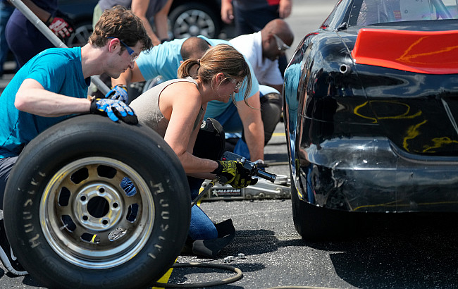 A woman changes a race car tire