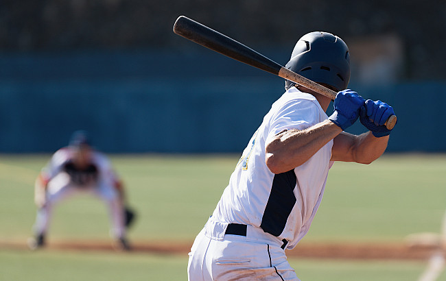 A baseball player prepares to the swing the bat as another player watches near a base on the baseball diamond