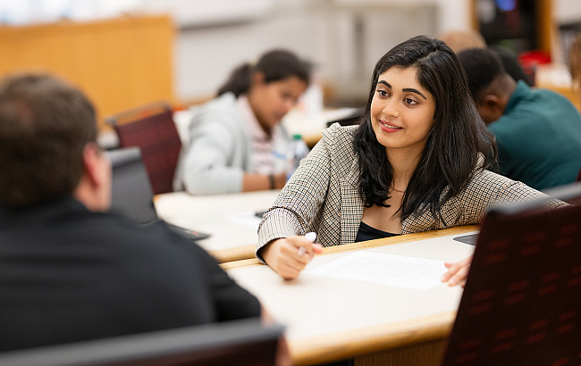 A woman wearing a blazer participates in group work in a lecture hall
