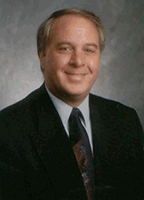 A man in a suit smiles.