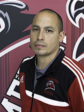 A man poses for a photo in a gymnasium.